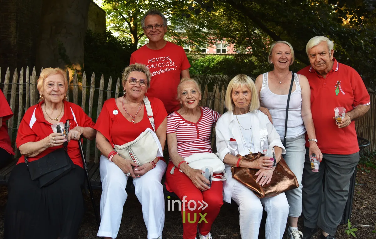 Plusieurs générations réunies sur un banc, en tenues rouges et blanches, pour le Doudou de Mons